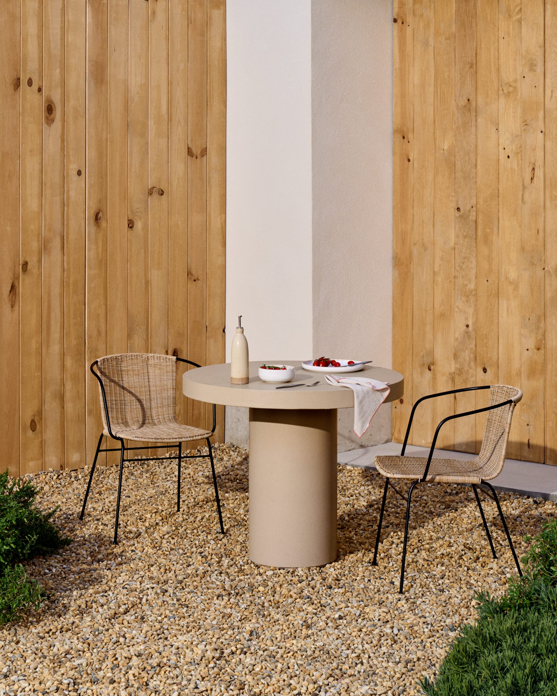 Eltiera stackable chair in synthetic rattan with black steel frame and armrests