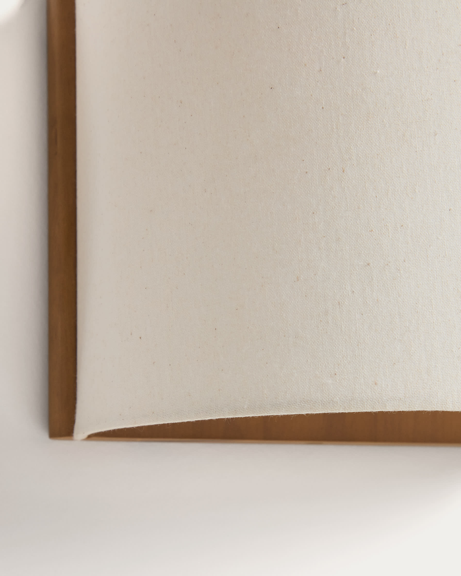 Umbran wall-mounted light fixture made from light brown rubberwood and beige linen