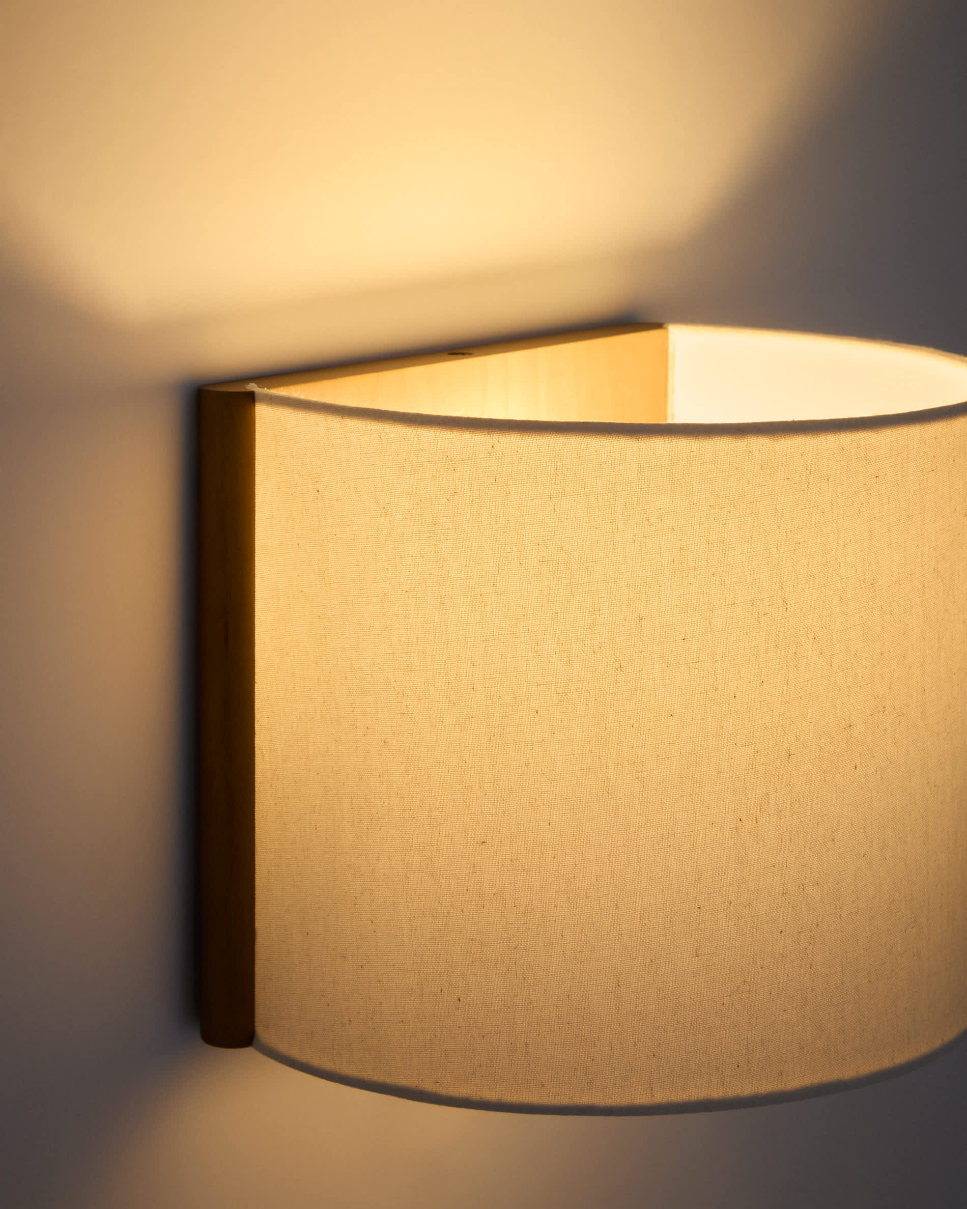 Umbran wall-mounted light fixture made from light brown rubberwood and beige linen