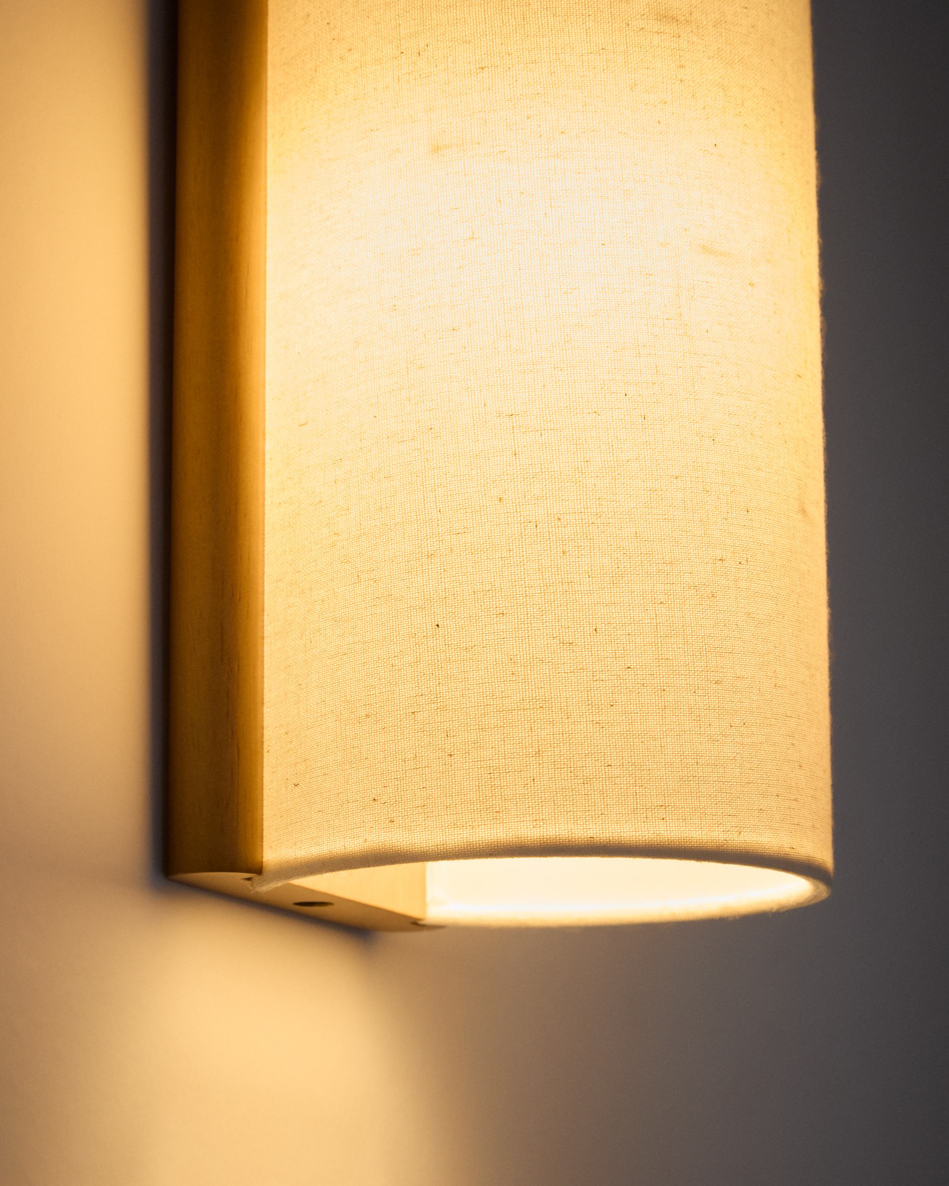 Umbran wall-mounted light fixture made from light brown rubberwood and beige linen