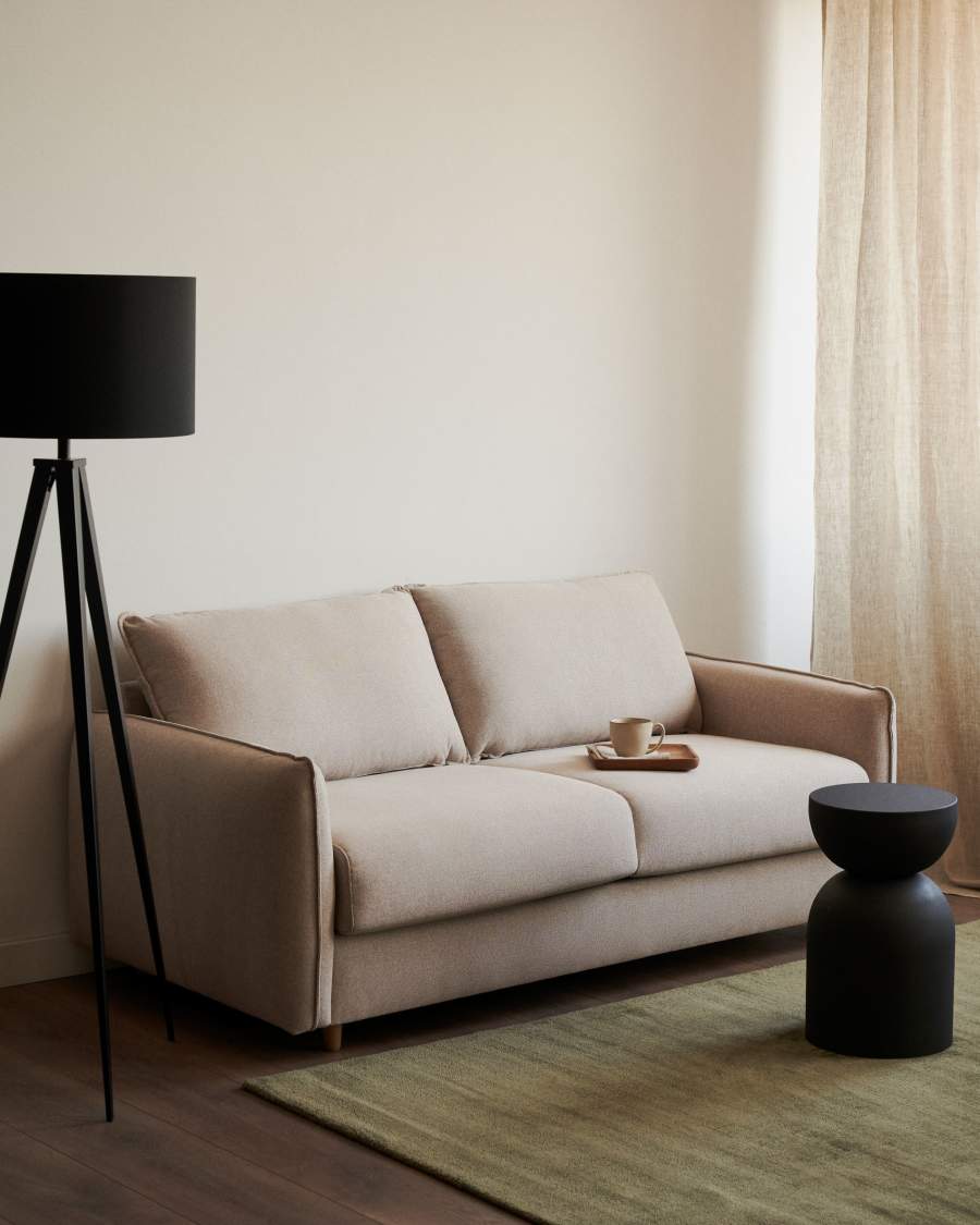 Canapé Carlota beige dans un salon sobre, lampadaire noir et table d'appoint noire à côté.