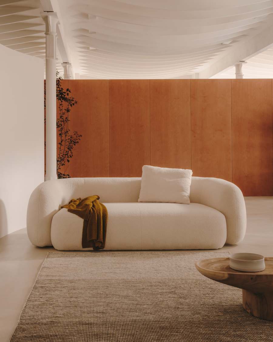 Canapé Martina 2 places en bouclette blanche cassée dans une pièce, plaid moutarde et coussin sur l'assise.