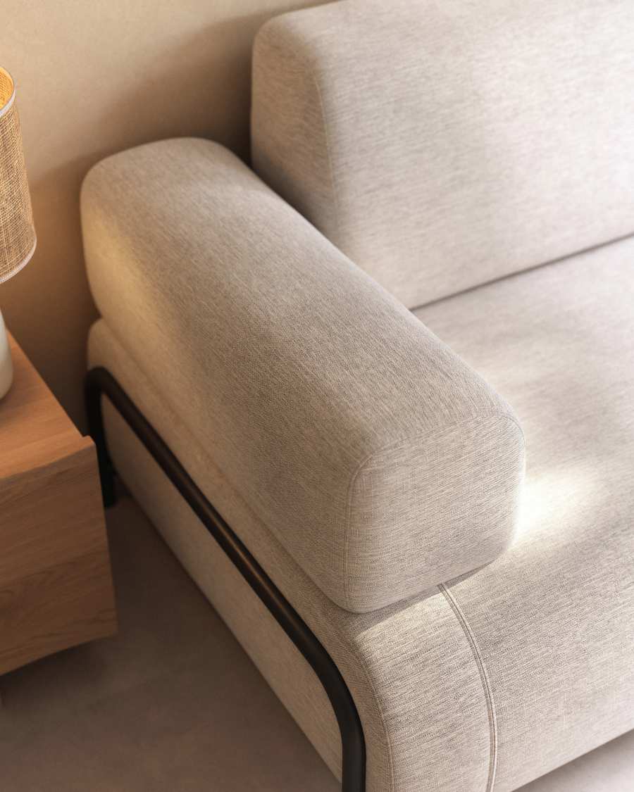 Gros plan de l'accoudoir arrondi en tissu beige du canapé Compo, près d'une lampe.
