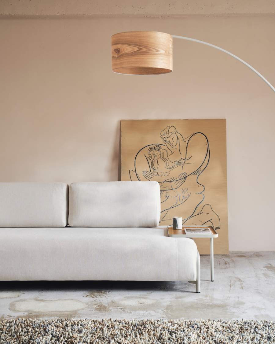 Canapé Compo blanc cassé avec petite table basse à droite, devant un tableau et une lampe arquée.