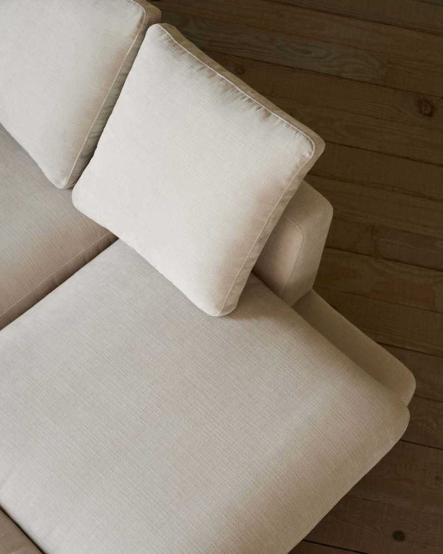Vue de dessus d'un coussin carré et de l'assise du canapé Gala beige sur parquet.