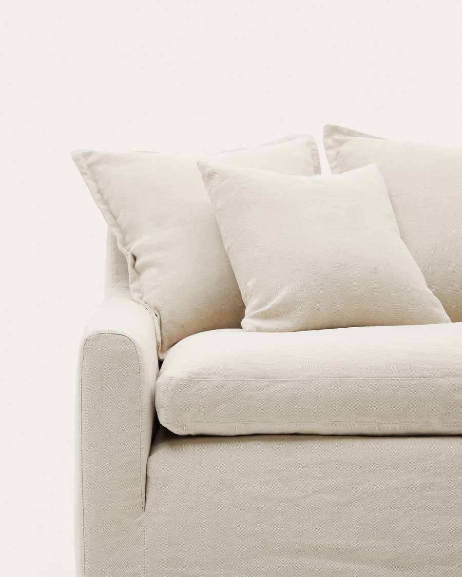 Gros plan de l’accoudoir large et des coussins beiges du canapé Zenira en lin.
