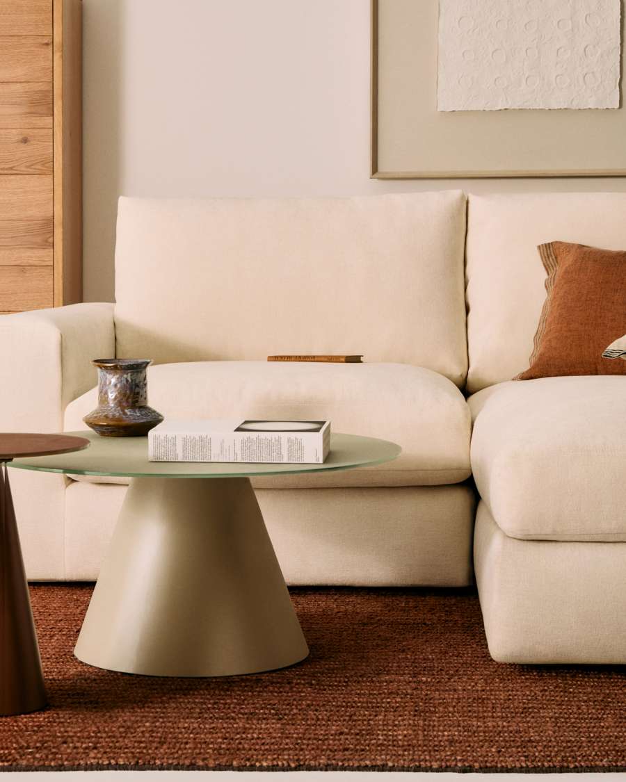 Gros plan d'un canapé Alea beige clair avec table basse verte et coussin terracotta dans un salon.