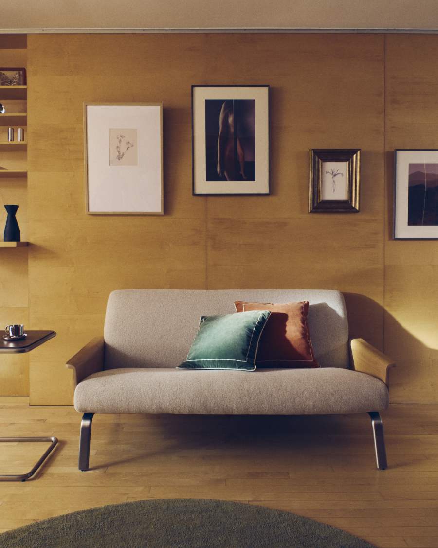 Canapé Amsen beige à deux places avec coussins vert et orange dans une pièce en bois clair.