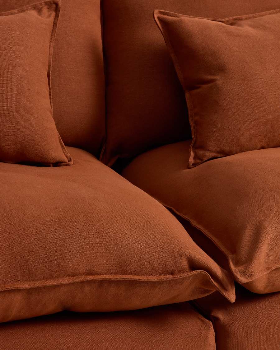 Gros plan des coussins et assises du canapé Anarela en lin terracotta, avec passepoil fin.