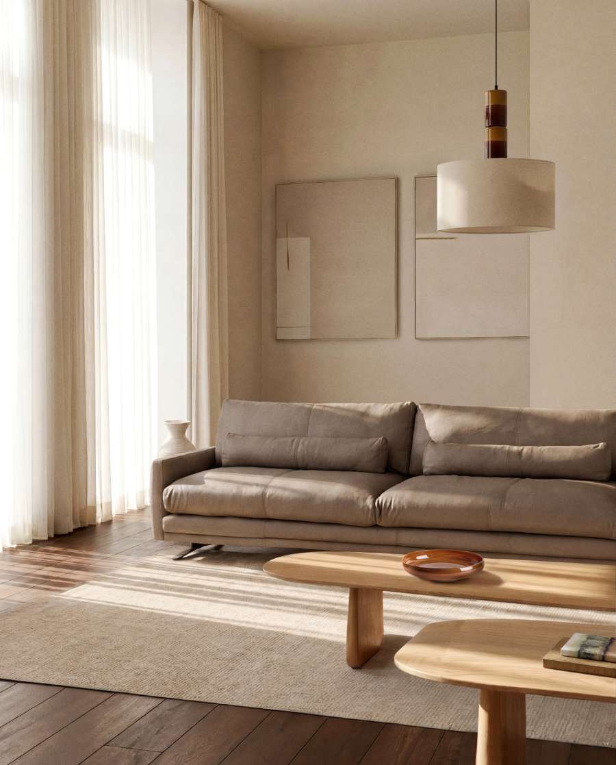 Canapé Veliro en cuir marron dans un salon clair, face à deux tableaux et une table basse en bois.