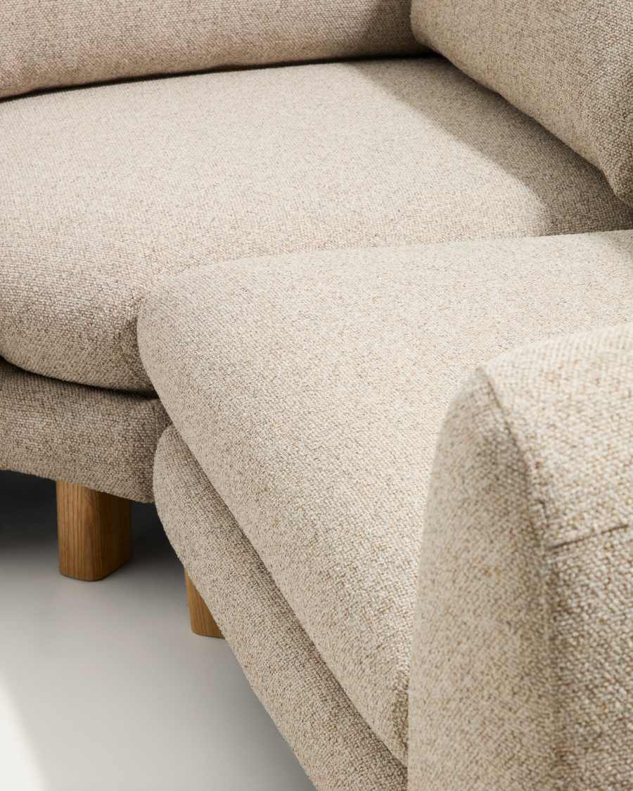 Gros plan de l'assise, de la méridienne et d'un pied en bois clair du canapé Vera beige.